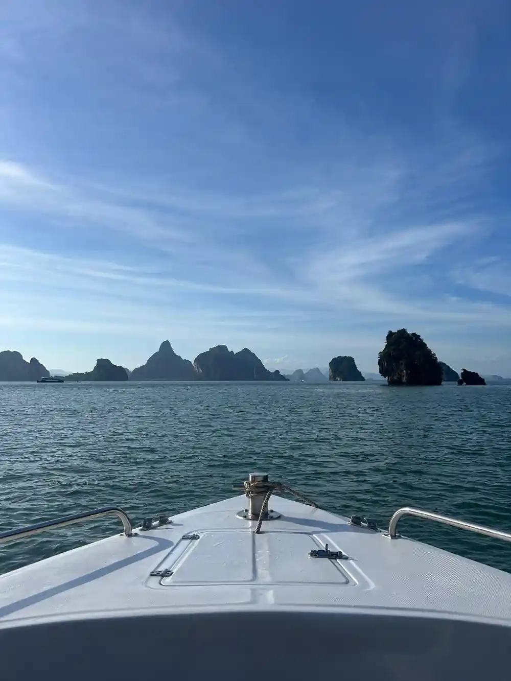 Boat bow approaching limestone islands in turquoise bay
