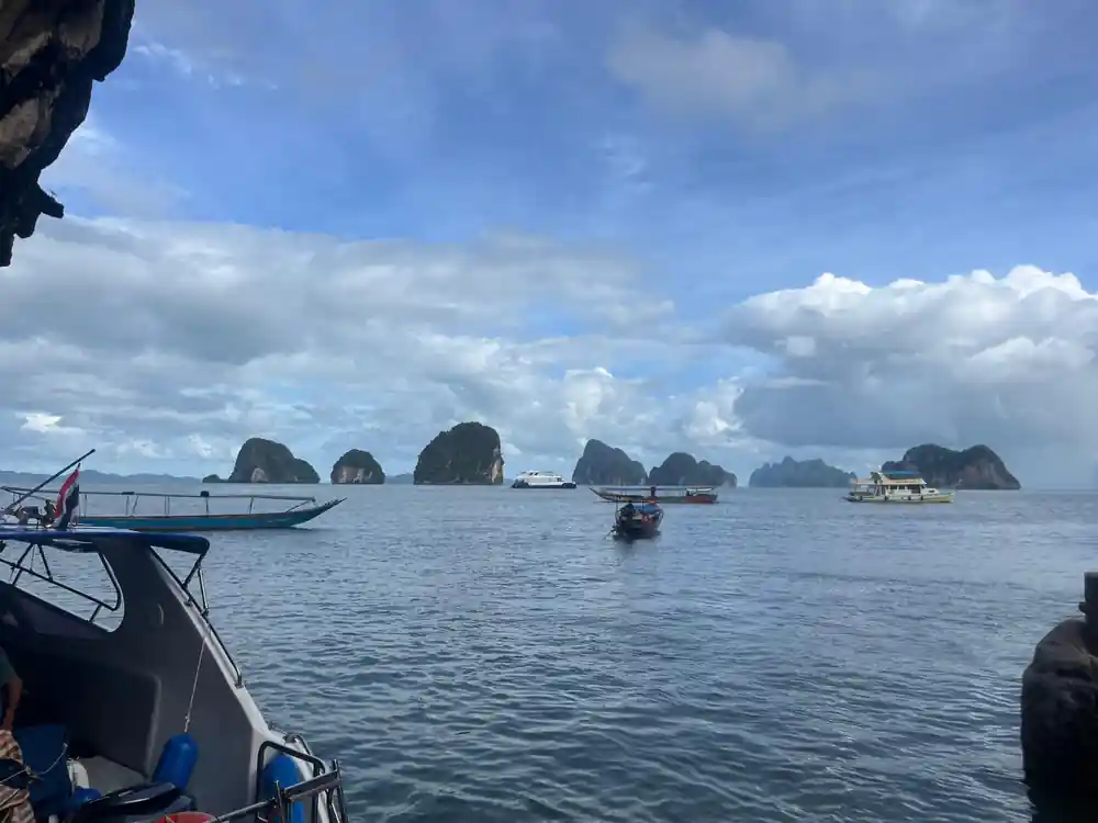 Boats anchored in turquoise water between limestone karst formations