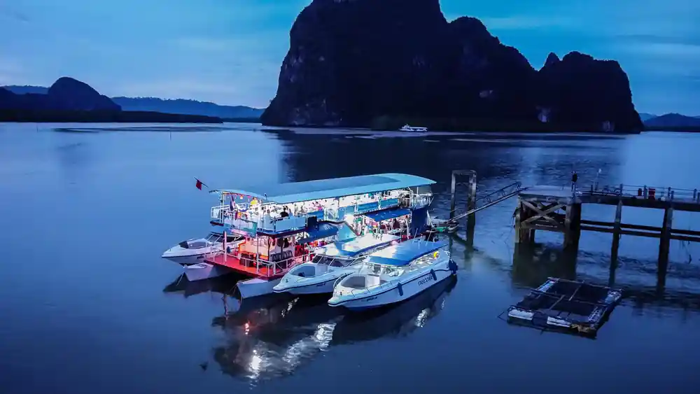 Fishing boats moored at twilight with dramatic limestone islands