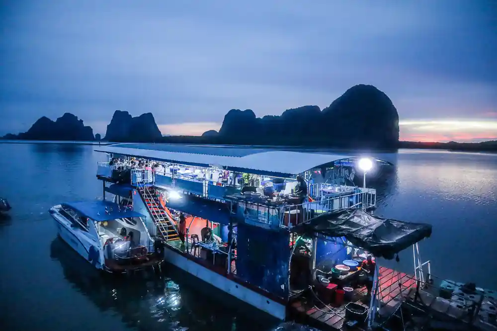 Floating platform restaurant with lights at dusk by islands