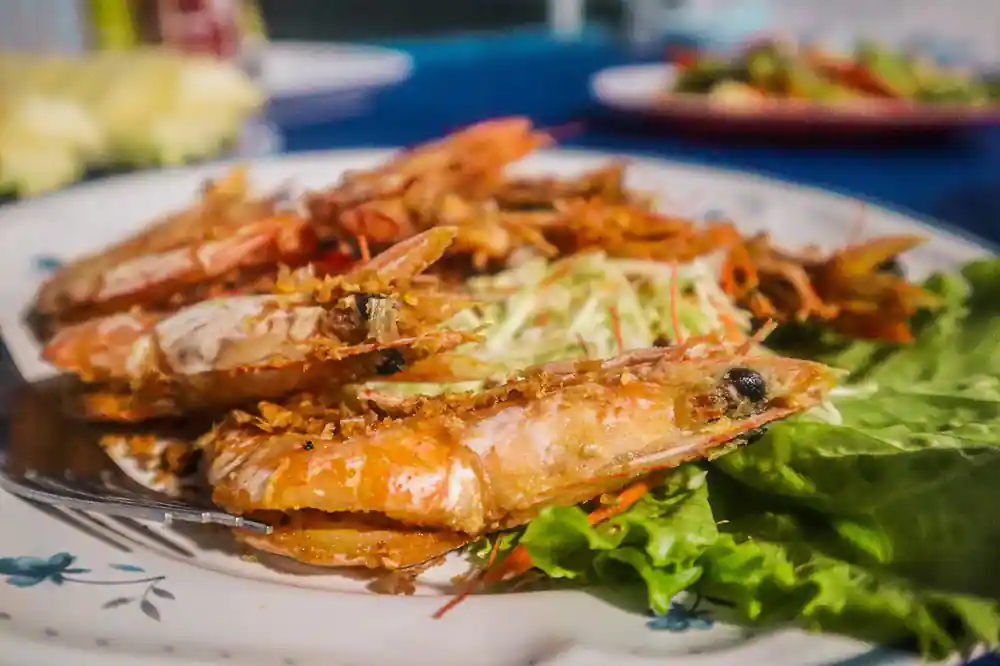 Grilled crabs with lettuce on white plate by water