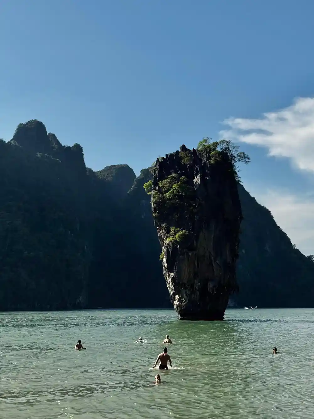Iconic limestone rock formation island with tourists swimming