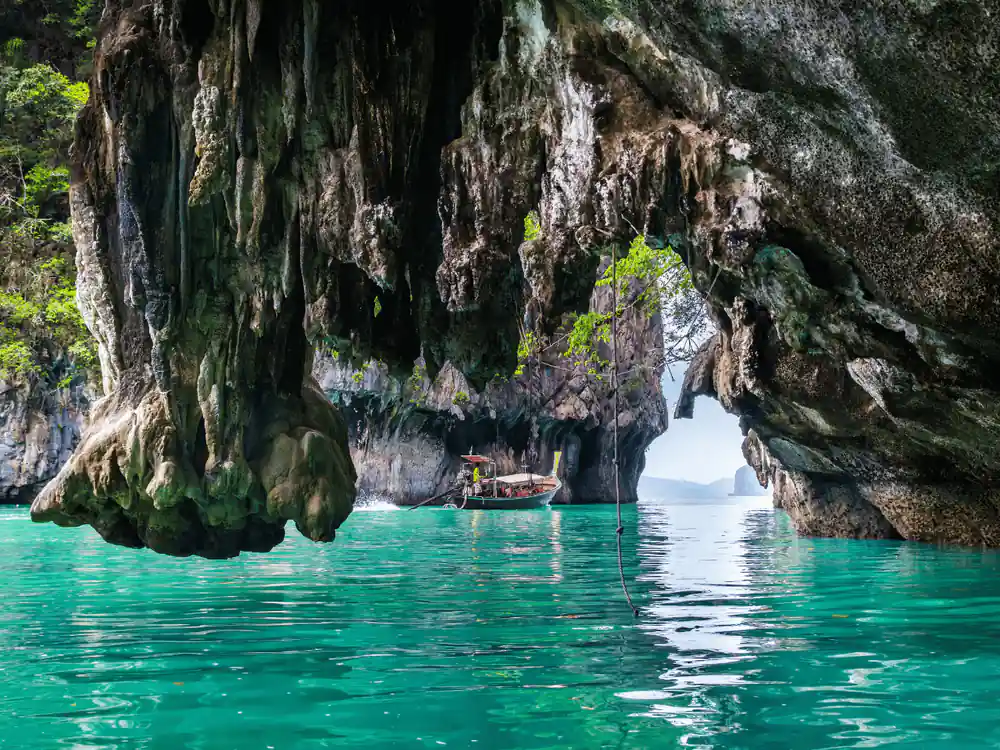 Limestone cave entrance with turquoise water and small boat