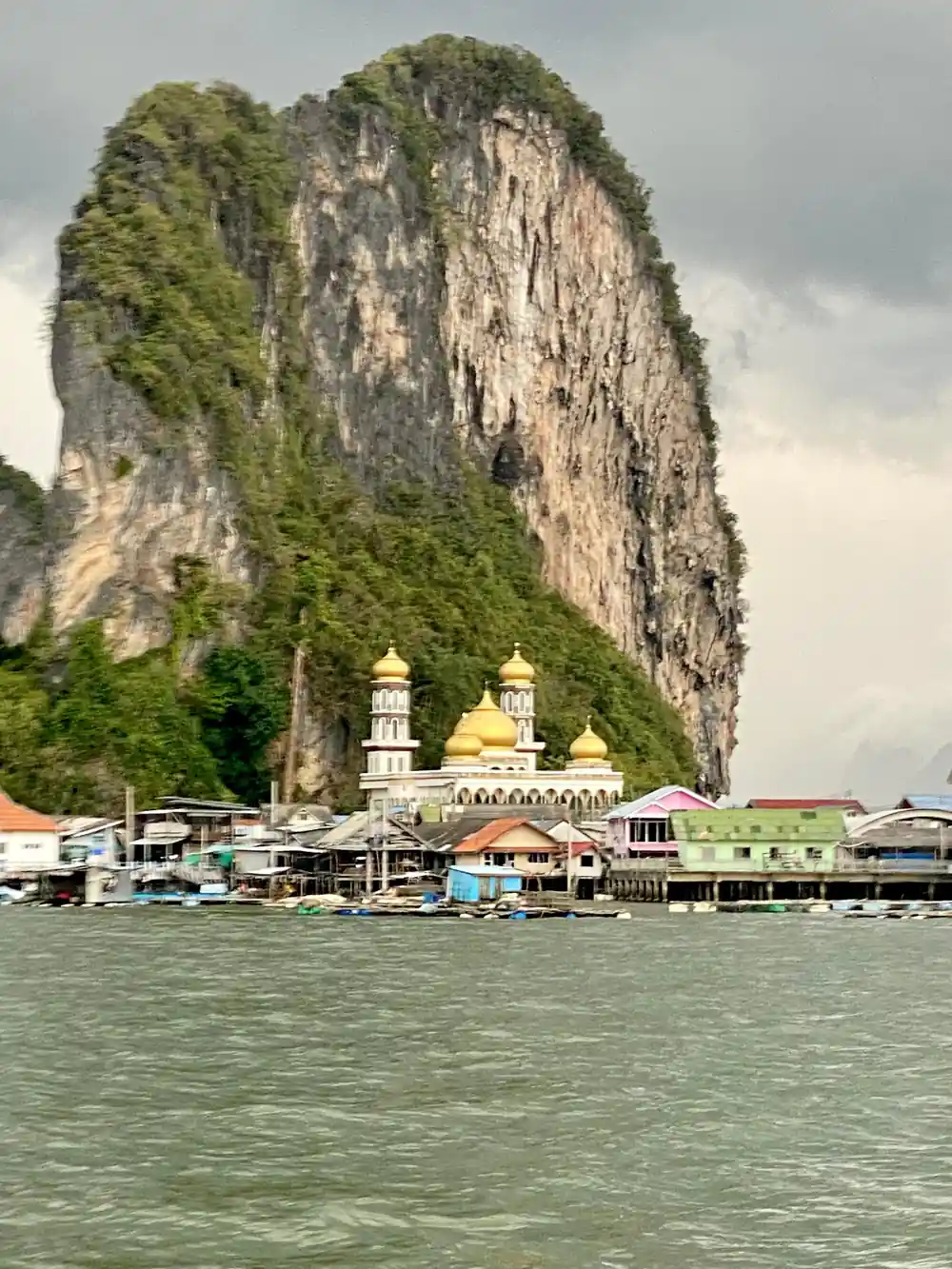 Mosque beneath tall limestone cliff over water