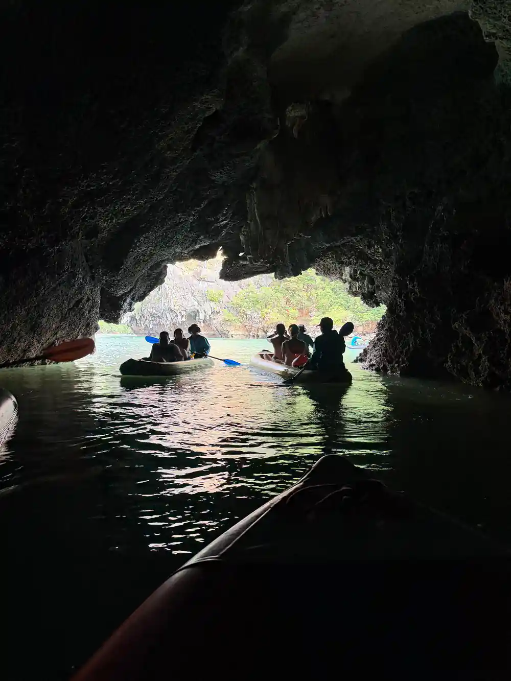 People in boats inside large cave opening