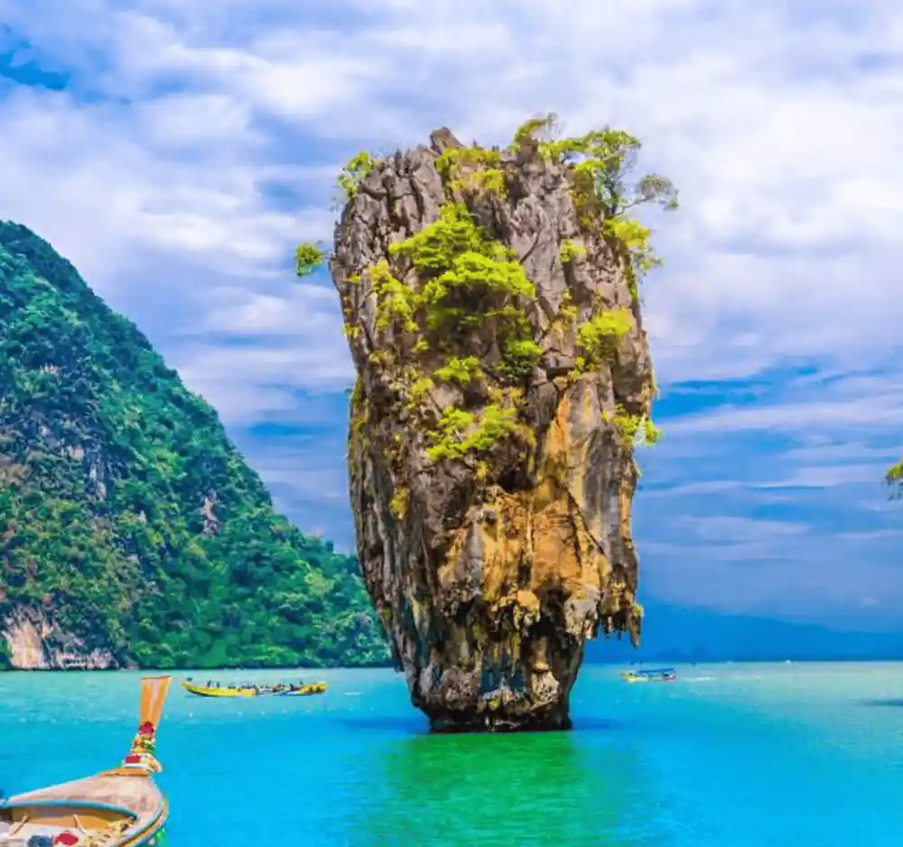 Single limestone pinnacle with boat in emerald sea