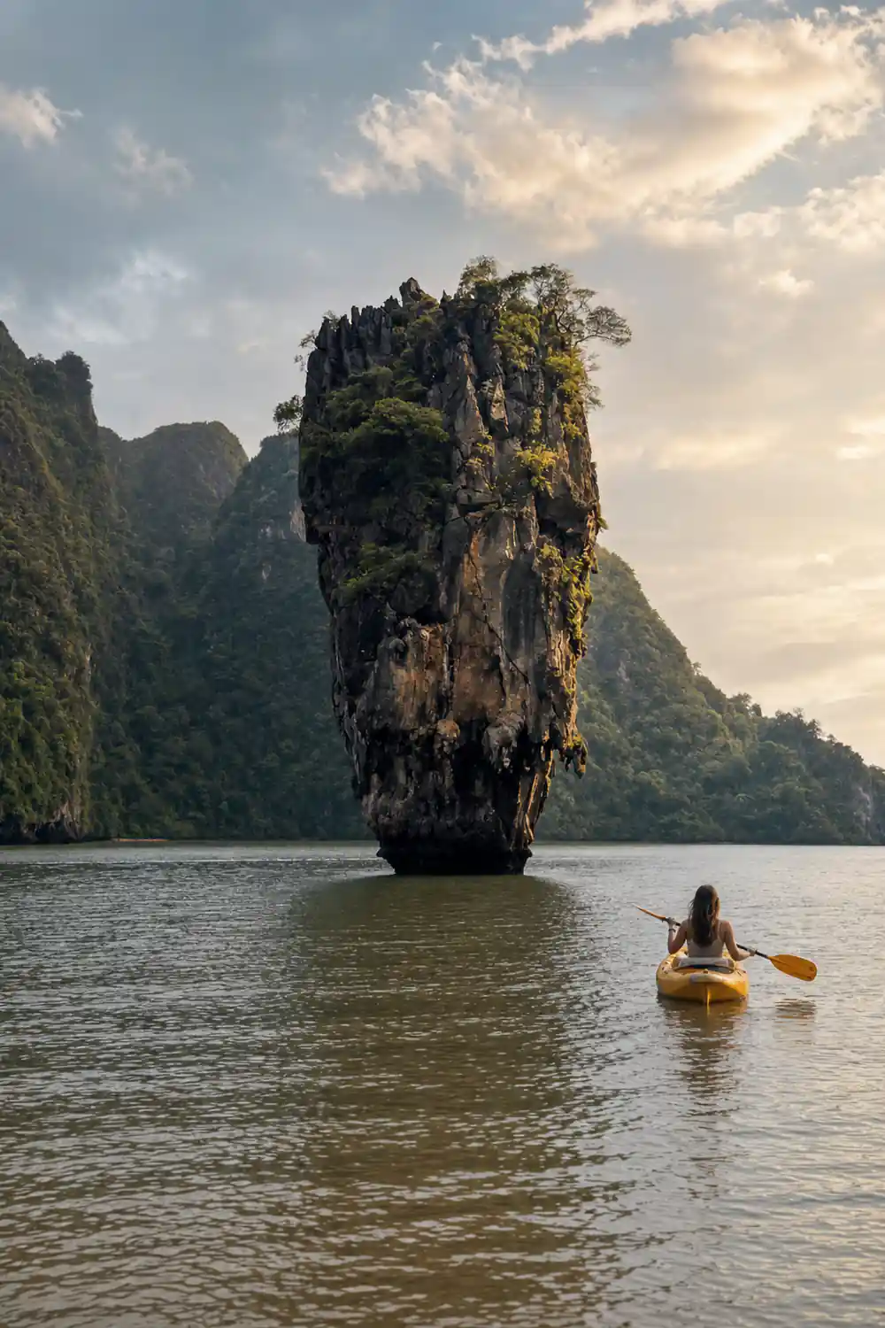 Single tall limestone island with vegetation and boat below