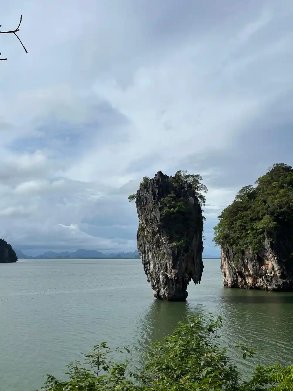 Single tall limestone pillar rising from blue-green shallow water