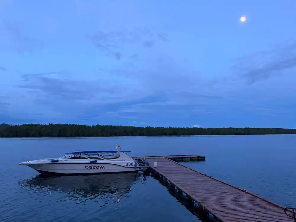 Speedboat moored at wooden dock at dusk