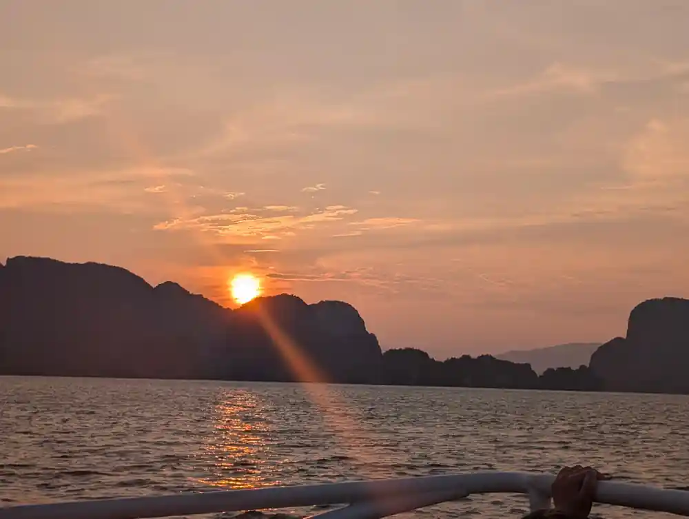 Sun setting between limestone islands over water