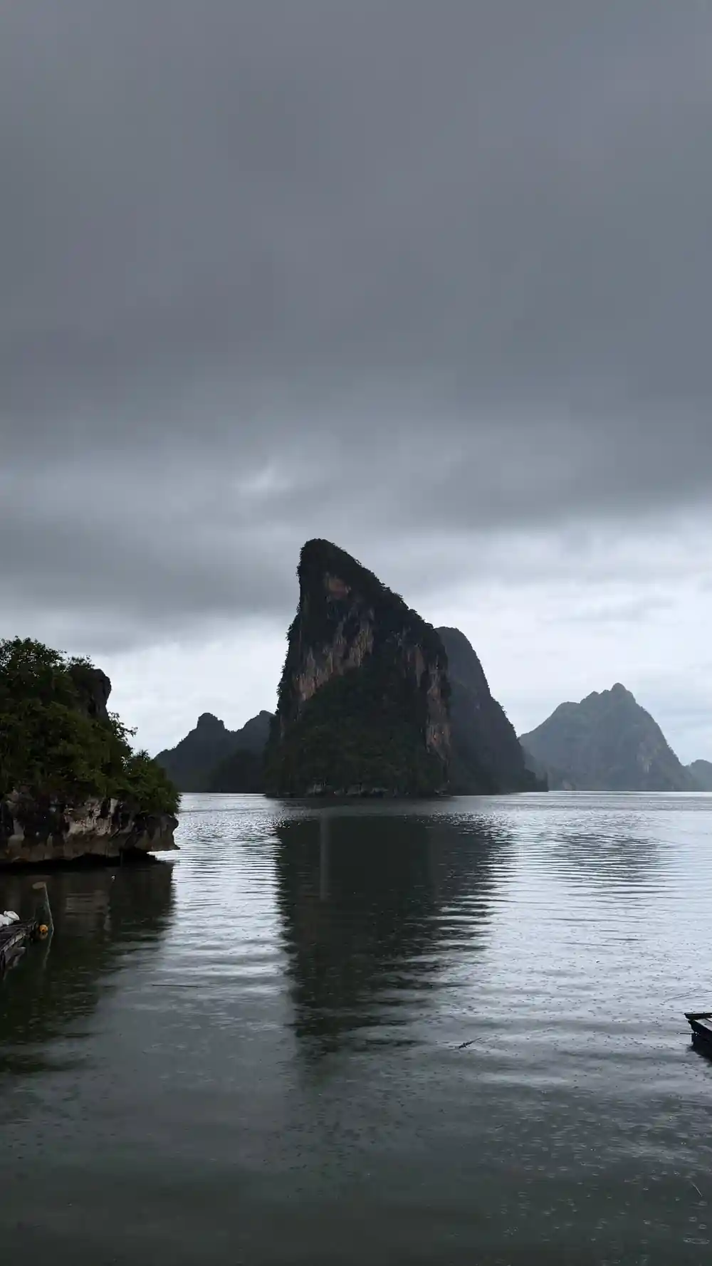 Tall limestone rock formation rising from calm water