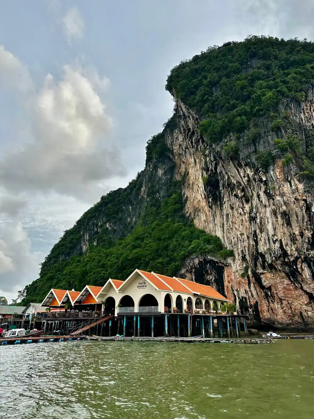 Traditional wooden house with orange roof and limestone cliff backdrop