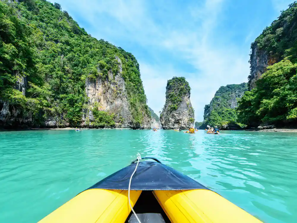 View from yellow kayak between steep green limestone cliffs