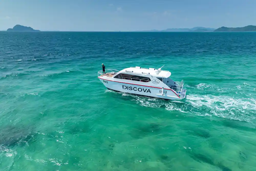 White boat named Discova in turquoise shallow water