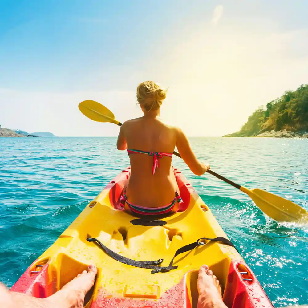 Woman kayaking in bright yellow kayak on turquoise water