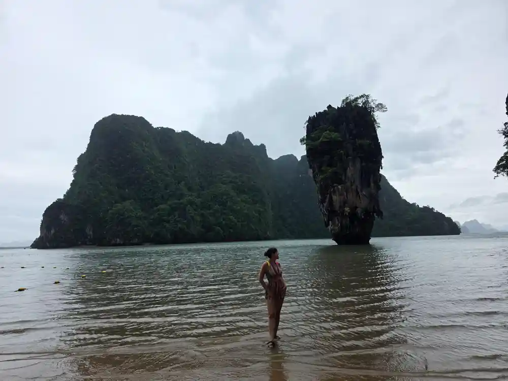 Woman wading in sea near tall limestone rocks