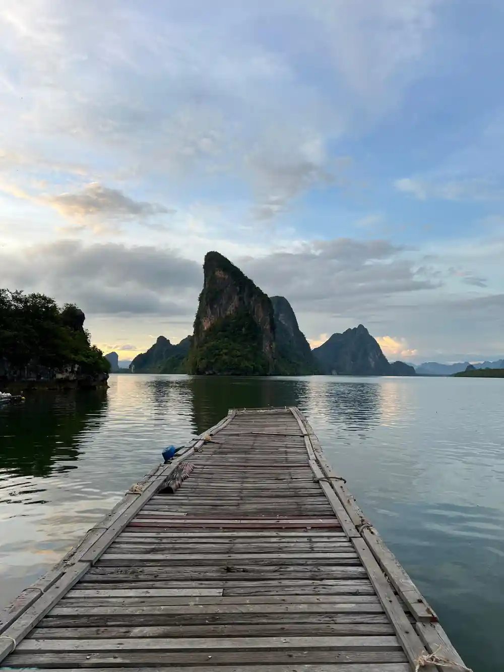 Wooden pier extending toward limestone islands at dusk